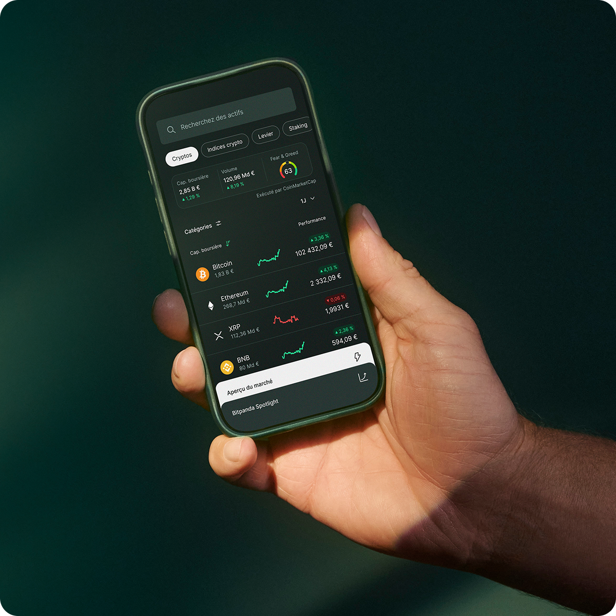 Hand holding a smartphone displaying a cryptocurrency app with various digital currencies, prices, and charts on a dark-themed interface.
