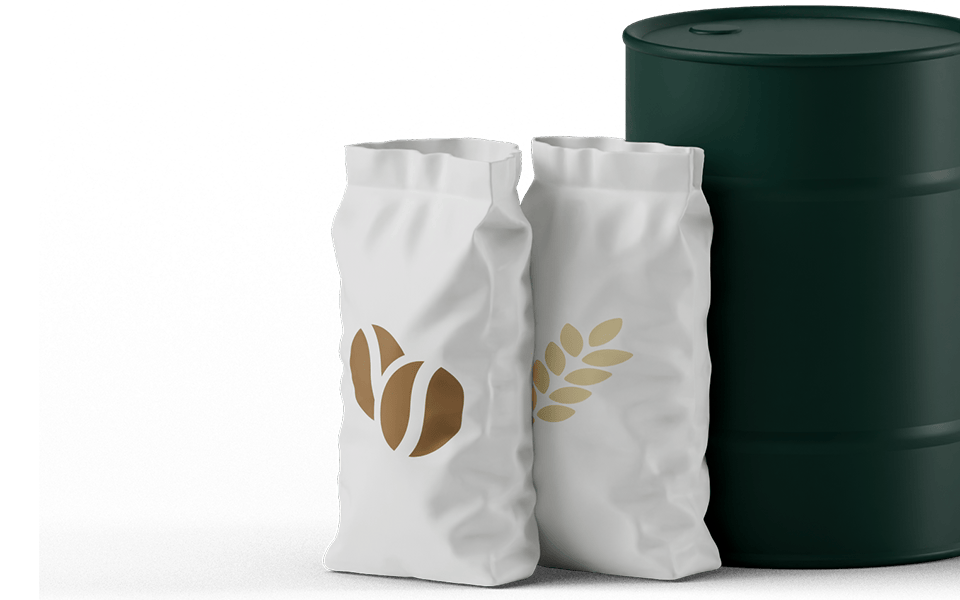 Two white bags with gold leaf and coffee bean designs stand next to a dark green barrel.